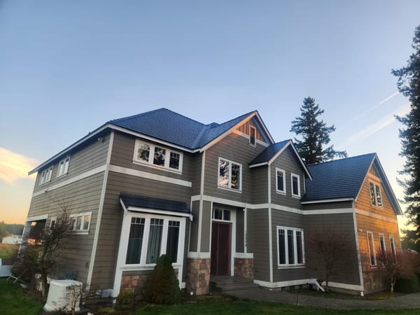 Two-story Craftsman home in Buckley WA with a complex multi-hip Interlock aluminum slate roof in Deep Charcoal, photographed at golden hour.