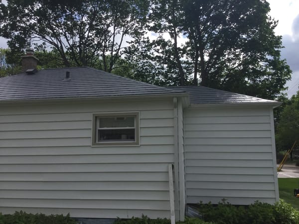 Charcoal Grey Interlock Slate aluminum roof on a white one-storey ranch home with a metal roof among tall, Madison, Wisconsin