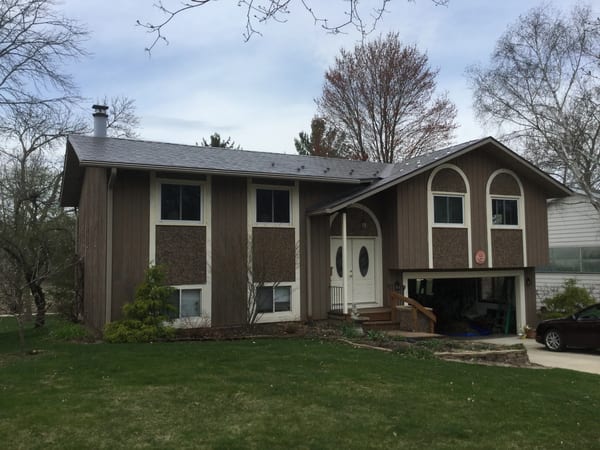 Weathered Interlock Slate aluminum roof on a brown single-storey home with a metal roof among tall, Madison, Wisconsin