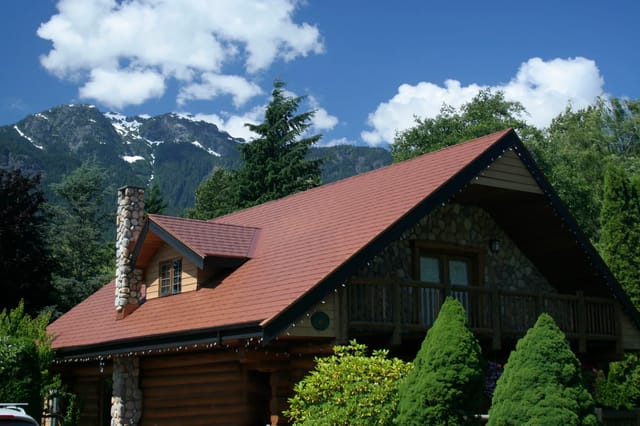 Aged Copper Interlock Slate aluminum roof on a brown chalet with a copper roof in a forested mountain, Brackendale, British Columbia
