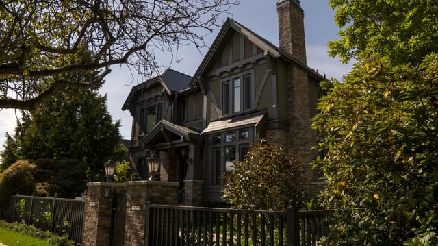 Deep Charcoal Interlock Slate aluminum roof on a brown two-storey craftsman home with dormers among tall, Vancouver, British Columbia