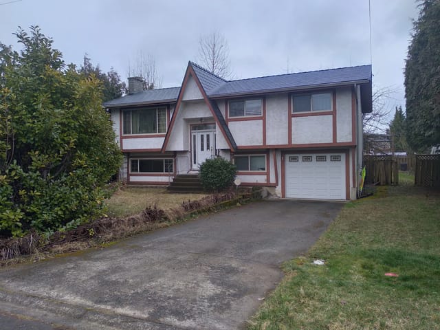 Deep Charcoal Interlock Slate aluminum roof on a white two-storey home with a metal roof among trees, Duncan, British Columbia