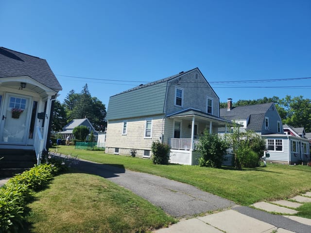 Hunter Green Interlock Slate aluminum roof on a two-storey house with a green metal roof in a suburban, Leominster, Massachusetts
