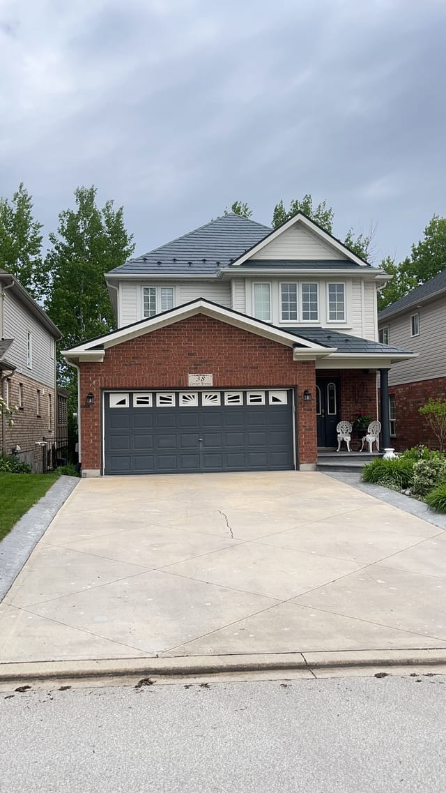 Two-storey brick home in Collingwood, ON with Interlock deep charcoal aluminum slate metal roofing on a multi-hip complex roof profile.
