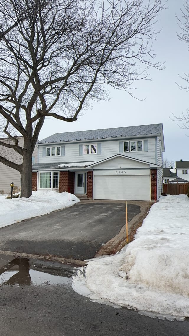 Two-storey colonial-style home in Orleans ON with Interlock charcoal grey aluminum slate metal roofing, brick lower facade, and attached garage.