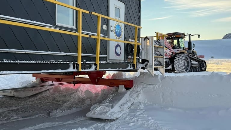 NSF SPOT Module featuring Interlock Metal Roofing being towed across Antarctic snow by a tracked vehicle during South Pole Overland Traverse expedition