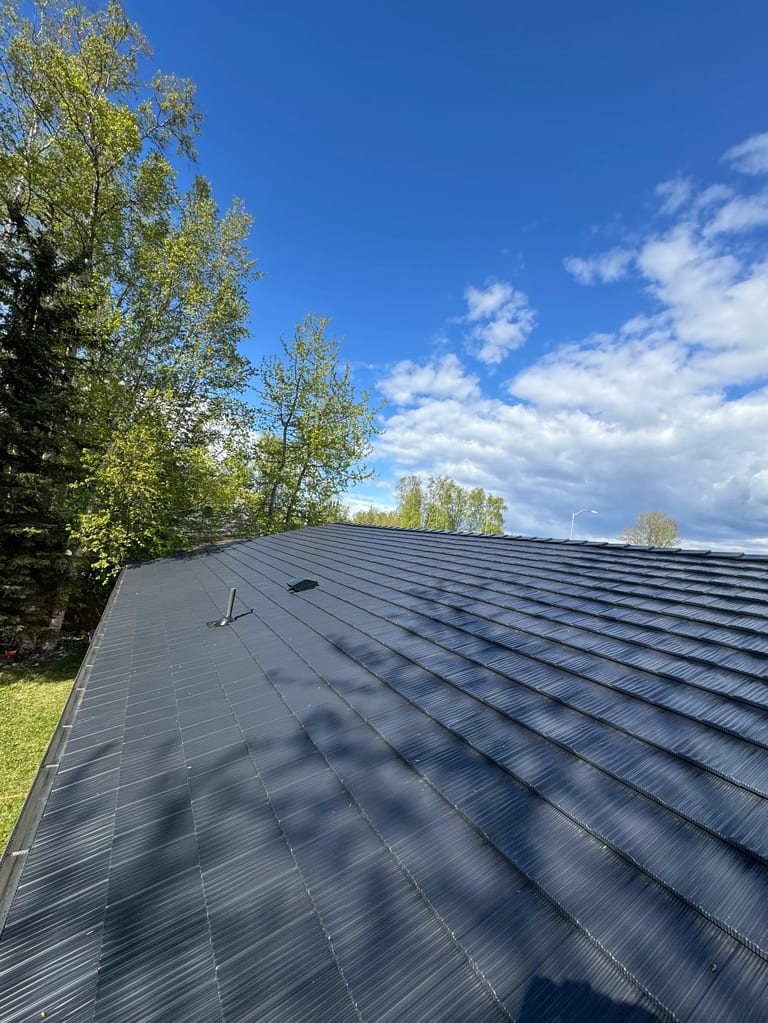 A metal roof installed by Interlock on a ranch-style single-family home in a suburban or urban area on a sunny day.