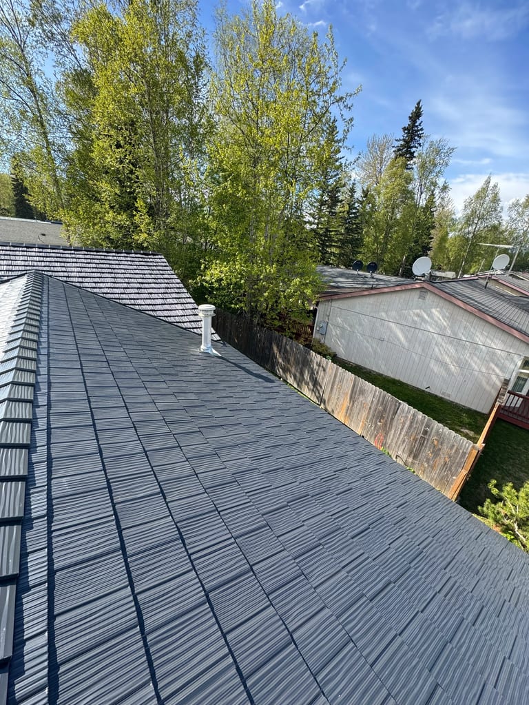 Metal roof on a ranch-style home with a lush green yard and blue sky