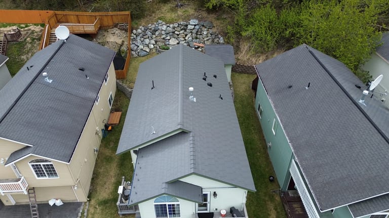 Aerial view of a house with a grey metal roof in a forested rural setting