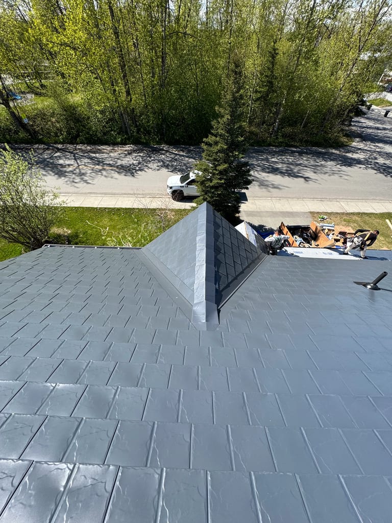 A gray metal roof on a single-family home in a rural setting.