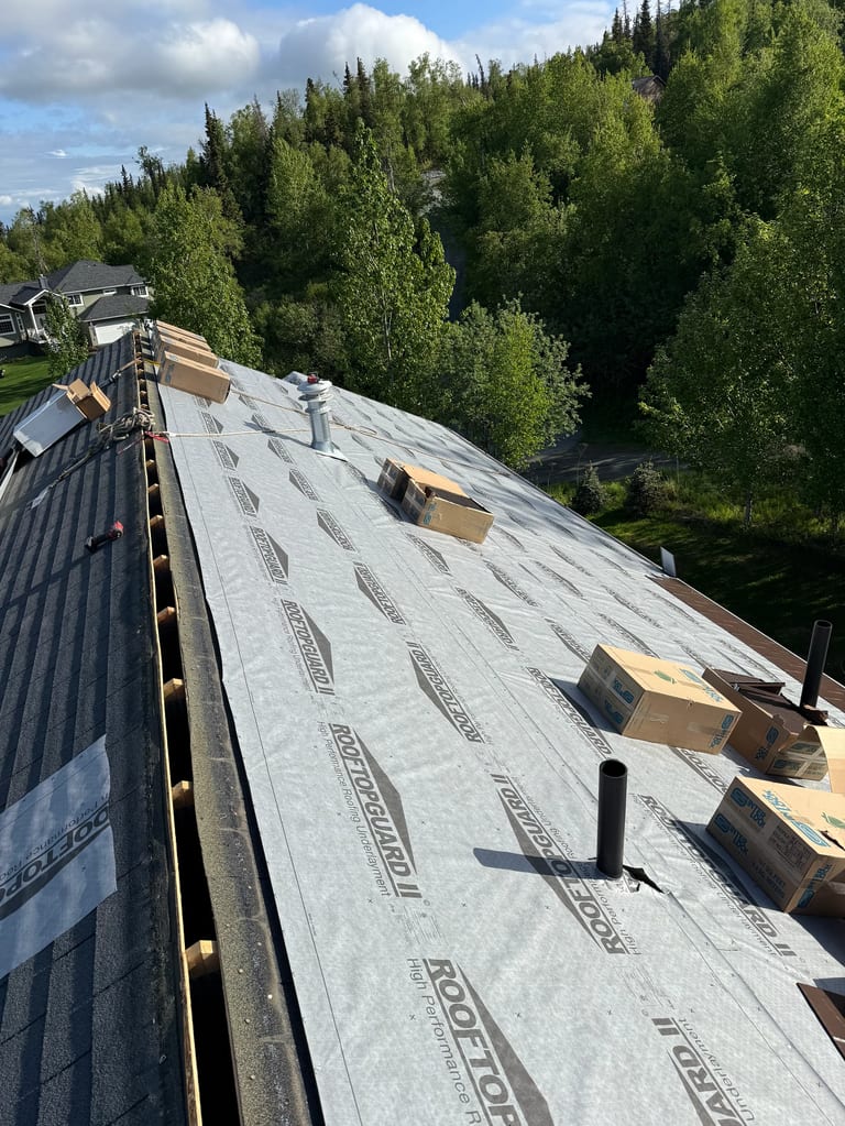 Metal roof underlayment installed on a modern single-family home in a forested rural setting