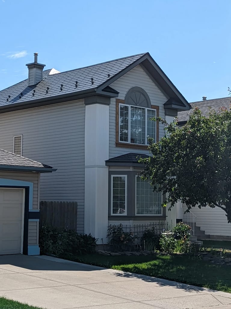 Deep Charcoal Interlock Slate aluminum roof on a grey two-storey home with dormers in a residential, Calgary, Alberta