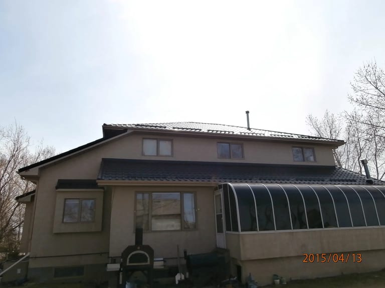 Black Interlock Tile aluminum roof on a tan single-storey home with a metal roof in rural Alberta, Redcliff, Alberta