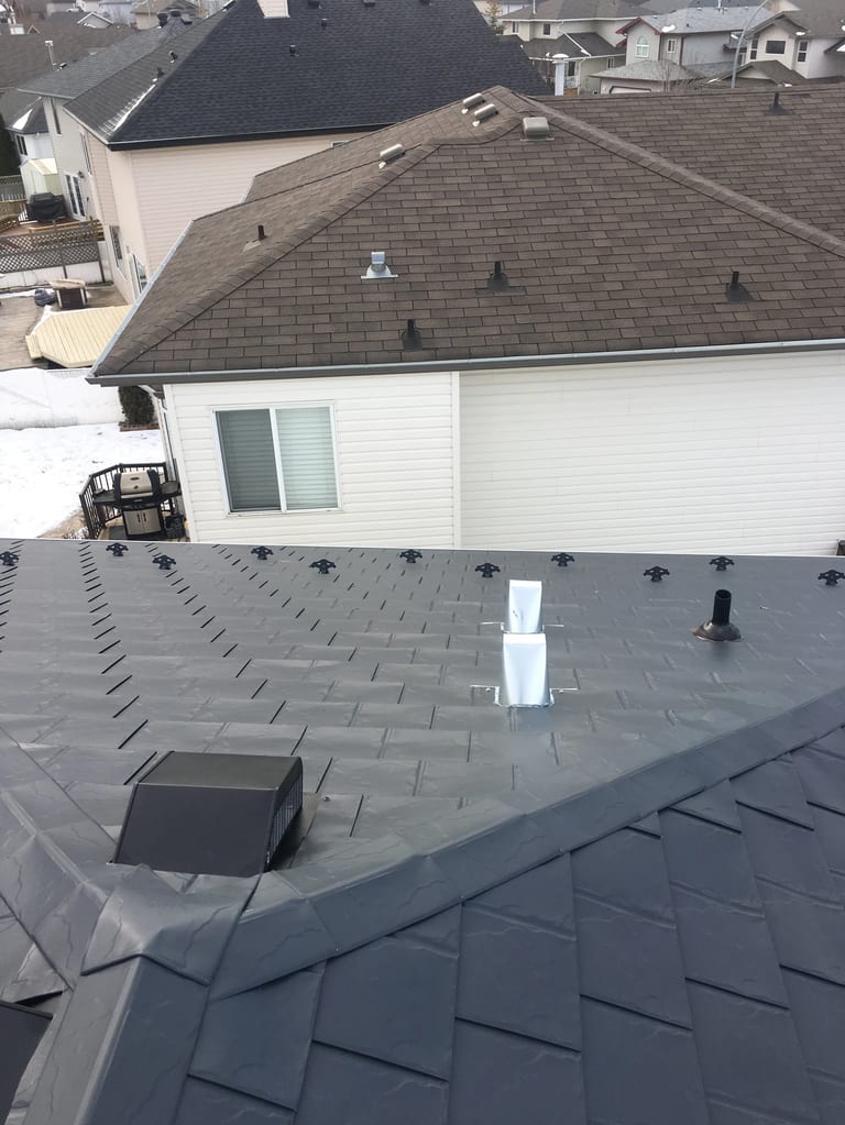 Deep Charcoal Interlock Slate aluminum roof on a white ranch style home with a chimney among snow covered, Fort Saskatchewan, Alberta