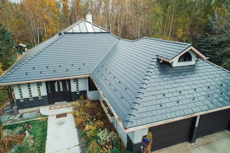 Black Interlock Slate aluminum roof on a white house with black metal roof in a wooded area, Spruce Grove, Alberta