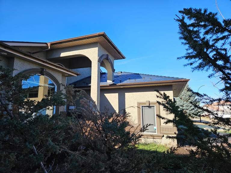 Black Interlock Slate aluminum roof on a single-storey home with a metal roof among trees, Red Deer, Alberta
