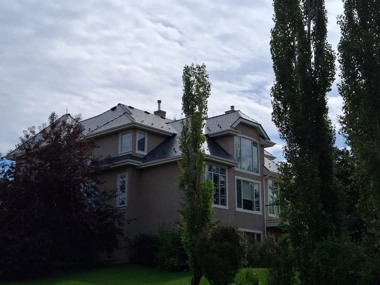 Deep Charcoal Interlock Slate aluminum roof on a beige modern single-family home with lush greenery in the, Calgary, Alberta