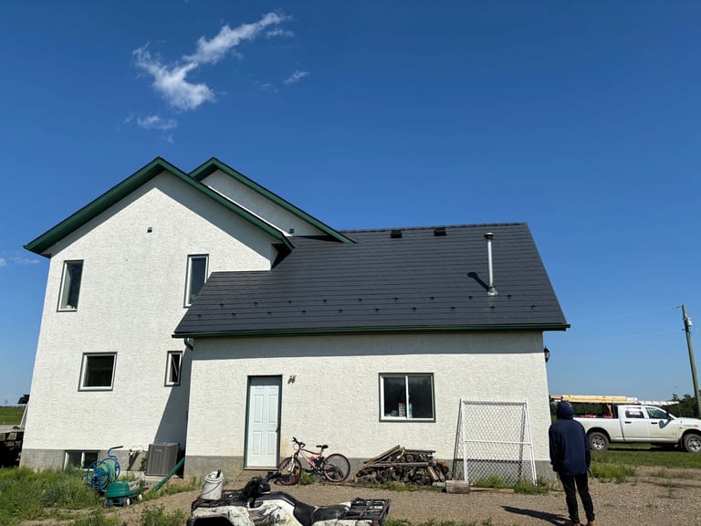 Deep Charcoal Interlock Slate aluminum roof on a white two-storey home with a metal roof in a rural setting, Fairview, Alberta