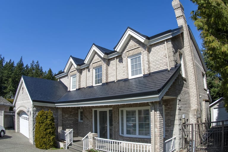 Black Interlock Slate aluminum roof on a beige two-storey Colonial home with dormers and a chimney, Surrey, British Columbia