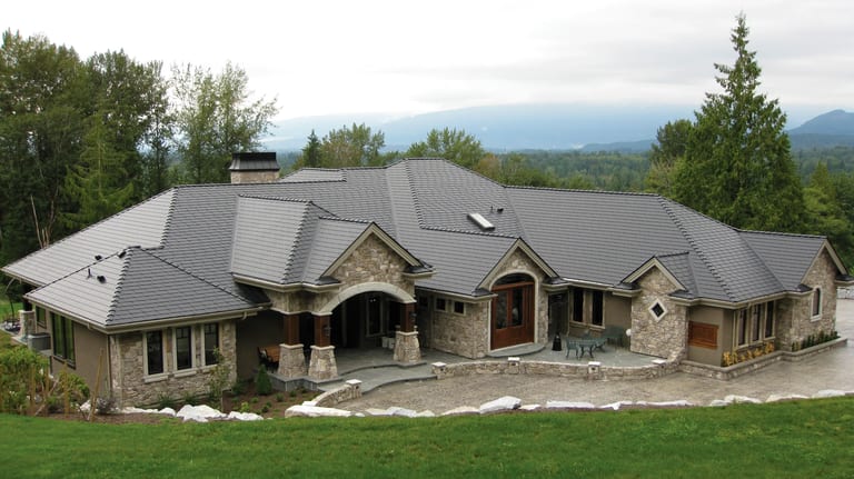 Charcoal Grey Interlock Slate aluminum roof on a stone ranch home with a metal roof in a forested mountain, Mission, British Columbia