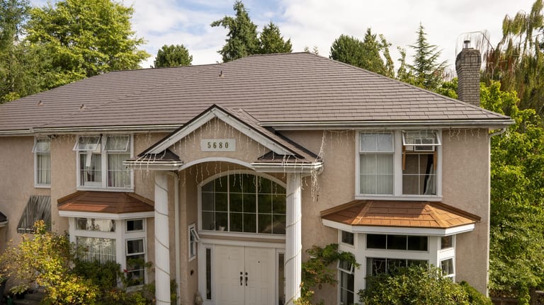 Tudor Brown Interlock Slate aluminum roof on a Tudor-style home with a brown metal roof among tall trees, Surrey, British Columbia