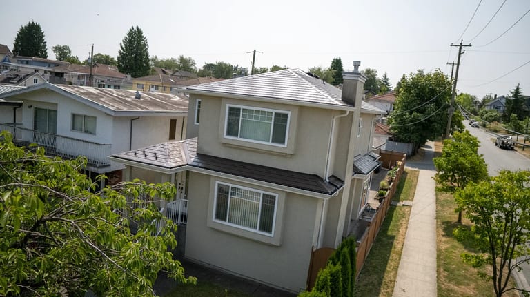 Colonial Brown Interlock Slate aluminum roof on a Colonial two-storey home with dormers among tall pines, Vancouver, British Columbia