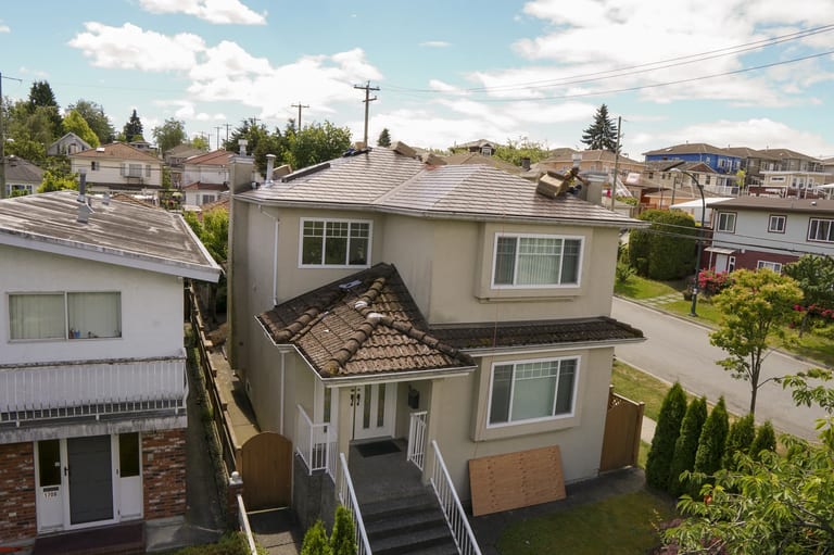 Colonial Brown Interlock Slate aluminum roof on a Colonial two-storey home with dormers among tall pines, Vancouver, British Columbia
