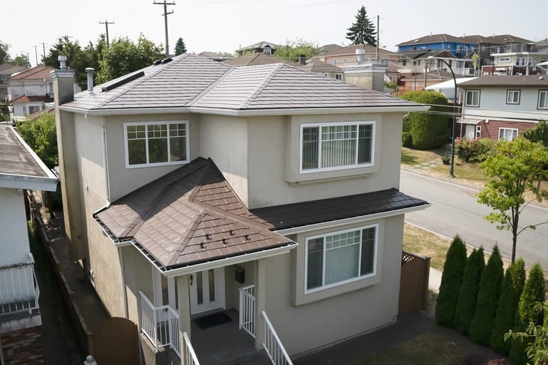 Aerial front view of a 2-storey stucco home in Vancouver with a complex multi-hip Interlock aluminum slate roof in Colonial Brown.