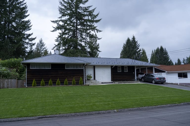 Deep Charcoal Interlock Slate aluminum roof on a brown ranch style home with a metal roof among tall trees, North Vancouver, British Columbia