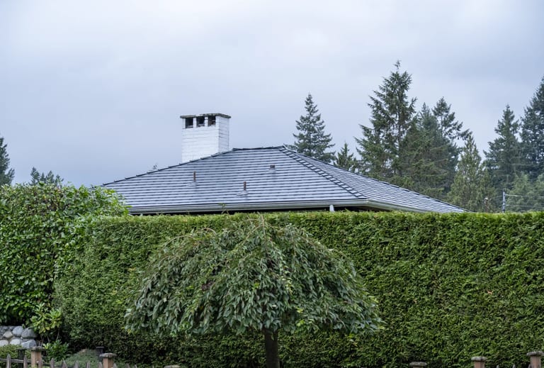 Deep Charcoal Interlock Slate aluminum roof on a Deep Charcoal metal roof on a house in a forested area, North Vancouver, British Columbia
