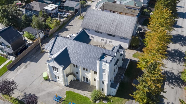 Deep Charcoal Interlock Slate aluminum roof on a white two-storey home with dormers in a residential area, Vancouver, British Columbia
