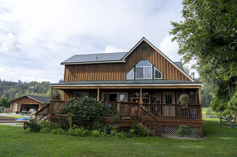 Hunter Green Interlock Slate aluminum roof on a two-storey chalet with a green metal roof in a forested, Langley, British Columbia