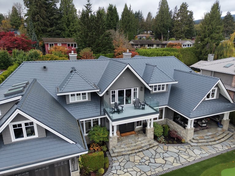 Deep Charcoal Interlock Slate aluminum roof on a grey two-storey home with dormers on a wooded mountainside, North Vancouver, British Columbia
