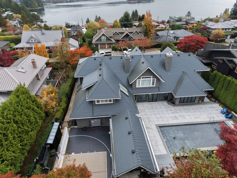 Deep Charcoal Interlock Slate aluminum roof on a modern home with a grey metal roof among autumn trees, North Vancouver, British Columbia