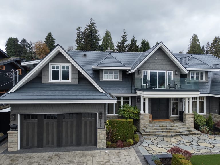 Deep Charcoal Interlock Slate aluminum roof on a grey home with stone accents among tall trees in the, North Vancouver, British Columbia
