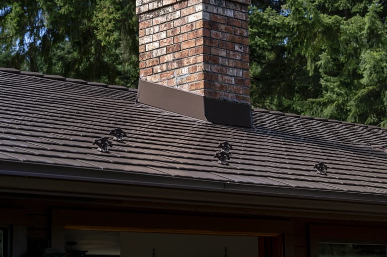 Colonial Brown Interlock Cedar Shingle aluminum roof on a brown colonial home with dormers among tall pines, Salt Spring Island, British Columbia