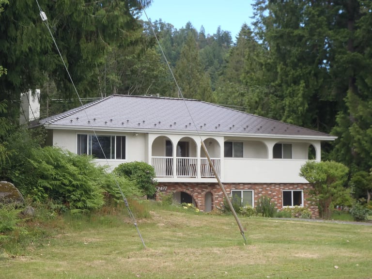 Tudor Brown Interlock Cedar Shingle aluminum roof on a brown one-storey home with a metal roof in a forested, Ladysmith, British Columbia