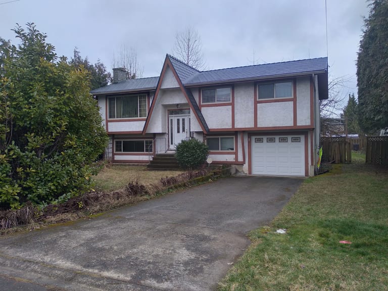 Deep Charcoal Interlock Slate aluminum roof on a white two-storey home with a metal roof among trees, Duncan, British Columbia
