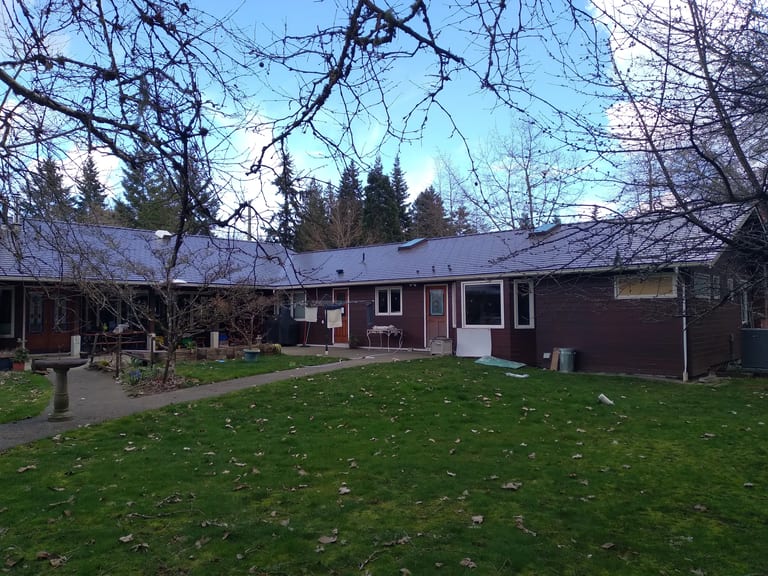 Tudor Brown Interlock Slate aluminum roof on a brown one-storey ranch home in a forest clearing, Duncan, British Columbia