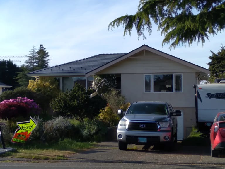 Deep Charcoal Interlock Slate aluminum roof on a tan home with a metal roof in a neighbourhood with houses, Victoria, British Columbia