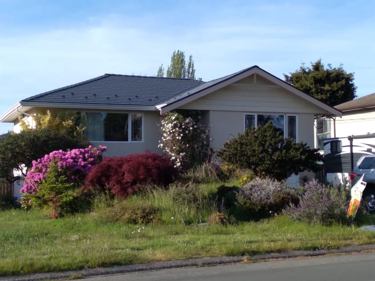 Deep Charcoal Interlock Slate aluminum roof on a beige ranch-style home with a brown roof in an, Victoria, British Columbia