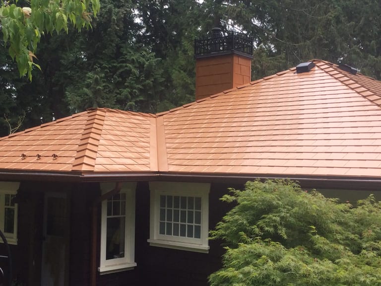 After: Copper Penny Interlock Slate aluminum roof on a home with copper penny metal roof among tall trees, Cowichan Bay, British Columbia