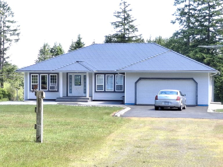 Deep Charcoal Interlock Slate aluminum roof on a light-coloured home with a metal roof in a coastal forest, Courtenay, British Columbia