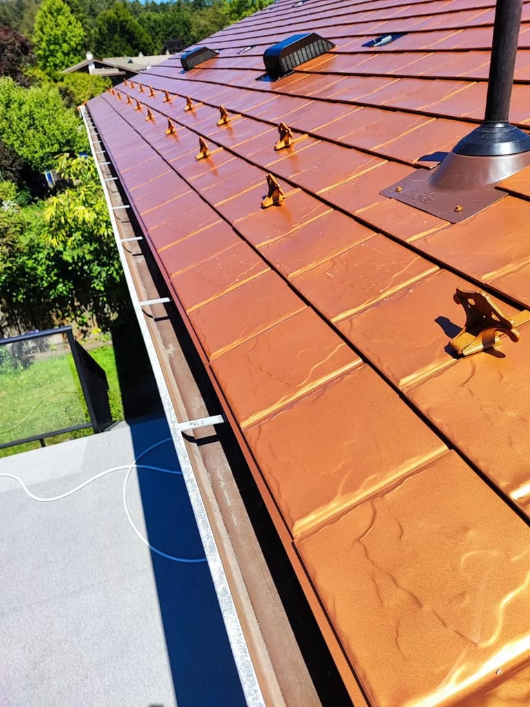 Copper Penny Interlock Slate aluminum roof on a single-storey house with copper roof in a forested, Victoria, British Columbia
