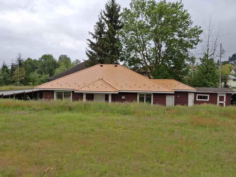 After: Copper Penny Interlock Slate aluminum roof on a red brick home with a brown metal roof in a forested, Ladysmith, British Columbia