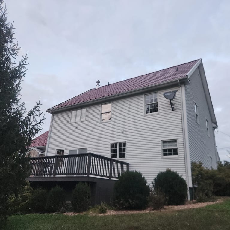 Rear-left view of a 2-story Colonial home in Oxford, CT featuring Interlock Tile Red Mediterranean aluminum tile metal roofing with a dark deck.