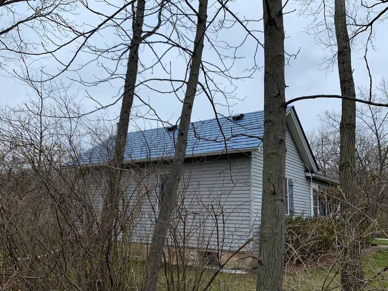 Royal Blue Interlock Slate aluminum roof on a grey home with dormers among bare trees, Woodstock, Illinois