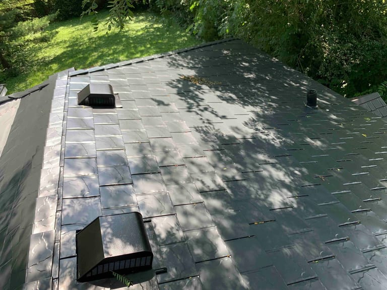 Black Interlock Slate aluminum roof on a black two-storey home with dormers among tall trees, Lombard, Illinois