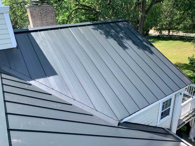 Black Interlock Standing Seam aluminum roof on a white house with a metal roof among trees and a lawn, Lake Forest, Illinois