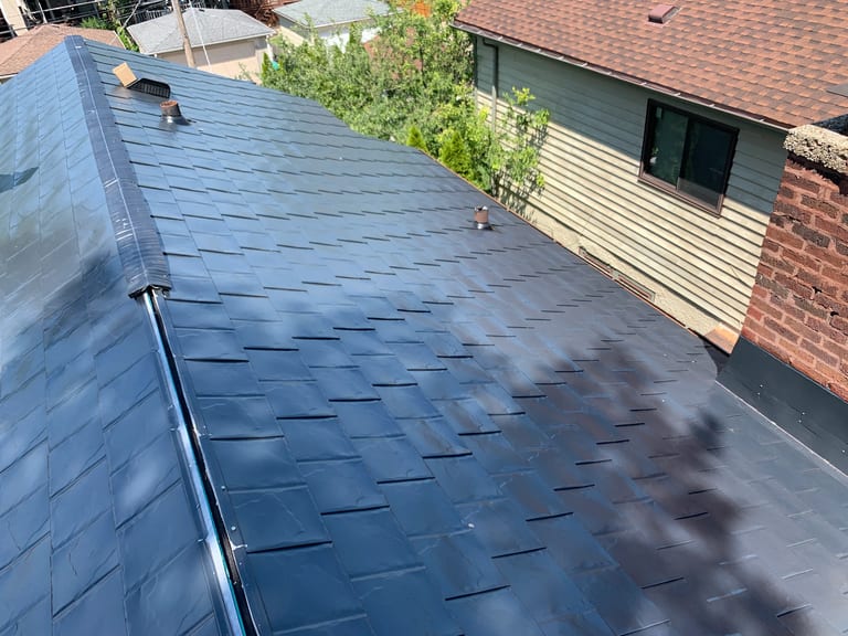 After: Black Interlock Slate aluminum roof on a two-storey home with brick and vinyl siding in a suburban, Oak Park, Illinois